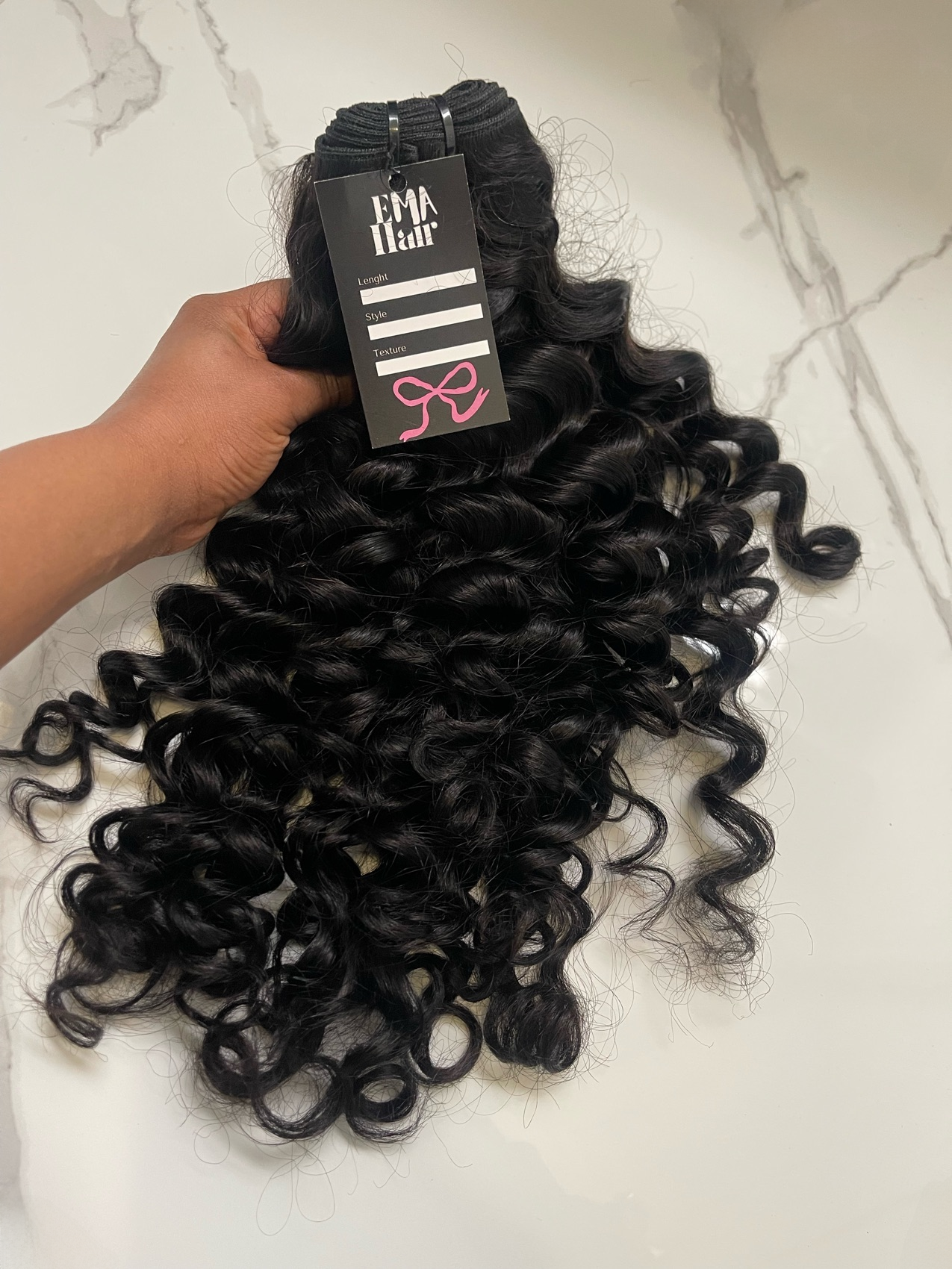 Curly hair extensions with a FMA Hair label on a white background